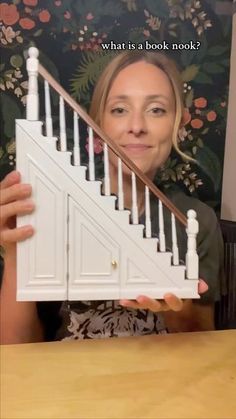 a woman holding up a dollhouse staircase with the caption, what is a book nook?