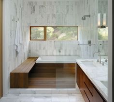 a bathroom with two sinks and a bathtub next to a window in the wall