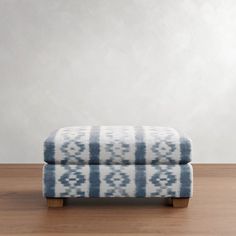 a blue and white ottoman sitting on top of a hard wood floor next to a wall