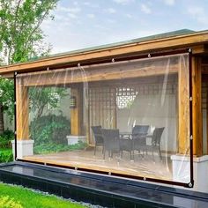 a covered patio area with chairs and table in the grass next to a pond, surrounded by trees