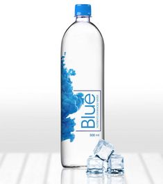 a bottle of blue water with ice cubes on the floor next to it,