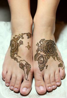 two feet covered in hendi tattoos on top of a white bedding sheet with the world map drawn on it