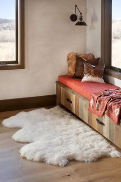 a white sheepskin rug sitting on top of a wooden bench next to a window