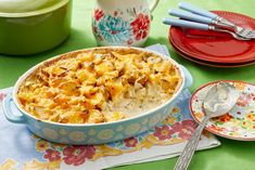 a casserole dish on a table with plates and utensils