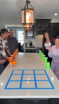 a group of people standing around a large table with cups on it and one person holding an orange cup