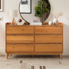 a wooden dresser with a round mirror above it