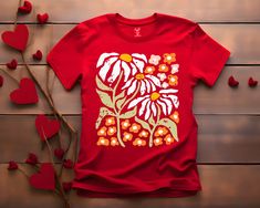 a red t - shirt with an image of a flower on it next to some hearts