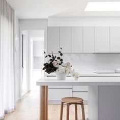 a white kitchen with an island and stools next to the counter top that has flowers on it