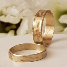 two gold wedding rings sitting on top of a table