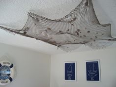 there is a fish net hanging from the ceiling in this room with two pictures on the wall