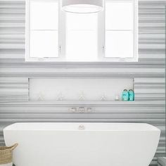 a large white bath tub sitting under two windows