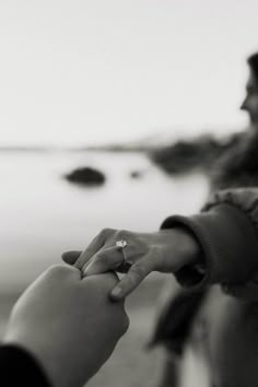 two people are holding hands and touching each other's fingers while standing on the beach