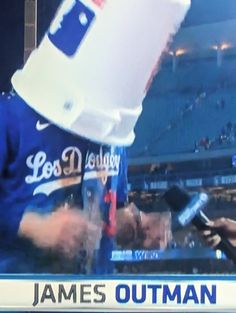 a baseball player is talking to someone on his cell phone while holding a water bottle