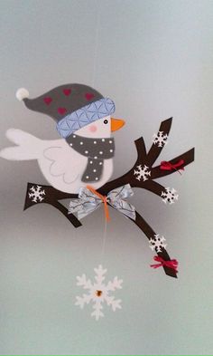 a white bird on a branch with snowflakes hanging from it's side