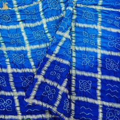 Fabric: Gajji Silk Weave – Bandhani with Ajrakh Pallu Color –Blue & Red Blouse – Ajrakh Note- There may be slight color variations due to photographic reasons. This is a hand-woven product and any irregularities in the weaving or pattern should not be taken as a defect. These irregularities make every handloom piece unique. Traditional Indigo Salwar Kameez For Festivals, Indigo Traditional Wear With Dupatta, Bollywood Style Indigo Dupatta For Navratri, Navratri Banarasi Silk Salwar Kameez With Bandhani Print, Unstitched Indigo Traditional Wear For Festivals, Festive Indigo Bandhani Print Traditional Wear, Unstitched Art Silk Salwar Kameez With Bandhani Print, Festive Indigo Bandhani Traditional Wear, Festive Indigo Traditional Wear With Bandhani Print