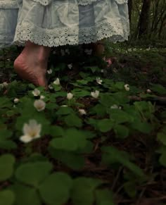 a woman's feet in the grass with white flowers