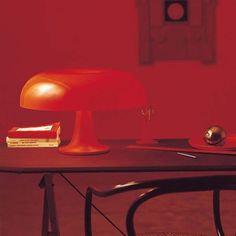 an orange lamp sitting on top of a wooden table next to a stack of books