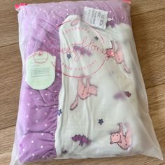 two baby swaddles are wrapped in purple and white sheets with pink pigs on them