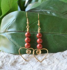 These earrings feature 3 6mm round red jasper beads strung on gold-plated wire shaped into a scroll heart at the bottom.       Earrings are approximately 2.5" long, including gold-plated ear wires.   Wire hearts are .75 inches wide.   Rubber ear nuts are included. Handmade Jasper Earrings As Gift, Elegant Adjustable Heart Beads Earrings, Elegant Heart Beads Earrings, Nickel-free Jasper Earrings As Gift, Nickel-free Jasper Earrings For Gifts, Red Jasper Jewelry, Wire Hearts, Jasper Jewelry, Earrings Heart