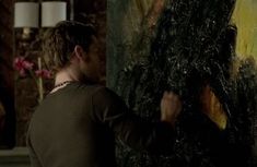 a man is painting on a large piece of art