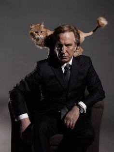 a man sitting in a chair with a cat on his head and another person standing behind him