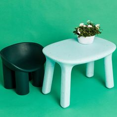 two stools and a small table with a potted plant on top, against a green background