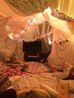 an unmade bed with lots of pillows and lights on the headboard in front of it