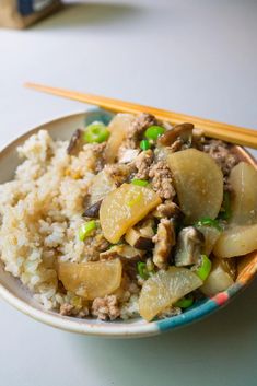 a plate full of food with chopsticks next to it on a white table