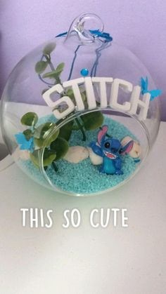 a glass bowl filled with blue sand and plants sitting on top of a white table