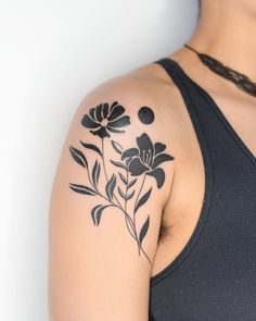 a woman wearing a black tank top has a flower tattoo on her left upper arm