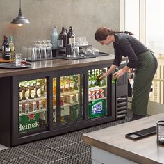 a woman standing over a counter filled with drinks