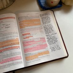 an open bible on a table next to a cup