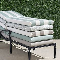 four mattresses stacked on top of each other in front of a green hedge wall