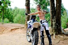 a beautiful woman standing next to a dirt bike