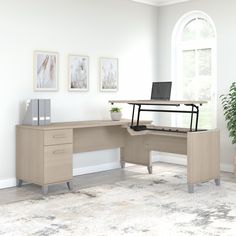 an office desk with a laptop on it in front of a window and potted plant