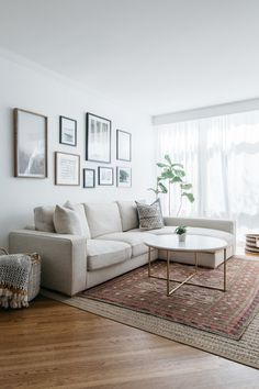 a living room with white furniture and pictures on the wall above it's coffee table