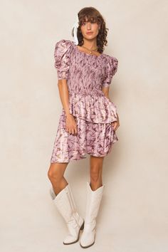 The Michelle Dress is the perfect mix of playful and chic. Made with a stunning purple floral knit fabric, this knee-length women's dress features a unique square neckline and 1/2 length fitted sleeves with a subtle puff at the cap. The asymmetrical tiered skirt adds a fun twist, while the hidden back zipper and smocked bodice provide a flattering fit. Maternity friendly too! Fitted Mauve Mini Dress With Ruffles, Fitted Purple Dress With Ruffle Hem, Purple Puff Sleeve Dress For Fall, Fitted Lavender Midi Dress With Ruffles, Fitted Lavender Dress With Ruffle Hem, Purple Fitted Tiered Dress, Fitted Ruched Mini Dress With Tiered Skirt, Chic Mauve Short Sleeve Dress, Fitted Midi Dress With Ruched Tiered Skirt