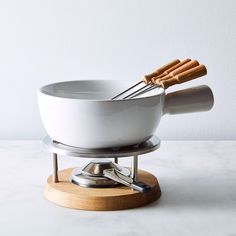 a white bowl with two cinnamon sticks sticking out of it and on top of a wooden stand