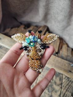 a person holding a giraffe brooch in their hand