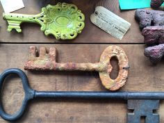 an old rusty key sitting on top of a wooden table next to rocks and other items