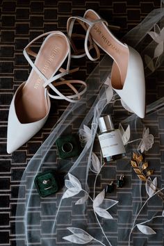 wedding shoes and accessories laid out on the floor next to a veil, bottle of perfume