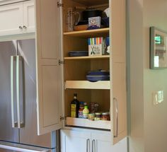 an open cabinet in the middle of a kitchen