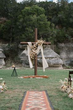 a wooden cross with flowers on it in the grass