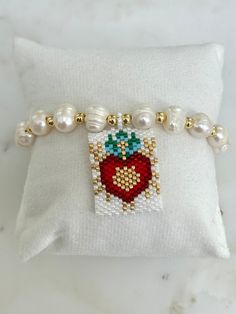 This Woven Heart Miyuki Beads Adjustable Bracelet is made with the following: Size & Material: - Features 8mm pearls and 4mm gold beads all strung on a cord  - The centerpiece showcases the Sacred Heart of Jesus, intricately crafted from small glass beads in white, red, gold, and turquoise. - The miyuki beads centerpiece measure 1'' x 1.25'' - The bracelet measures approximately 11'' long  - Adjustable cord for perfect fit The ideal gift for those devoted to the Sacred Heart of Jesus, perfect fo Pearl Beaded Bracelets With Heart Beads, Heart-shaped Beaded Pearl Bracelet Gift, Pearl White Beaded Bracelets As Gift, White Pearl Bracelet With Heart Beads, Pearl Bracelets With Heart Beads, Pearl White Beaded Bracelets With 8mm Beads For Gift, Heart Shaped Beaded Bracelet With Letter Beads As Gift, White Heart Bracelet With Pearl Charm, Heart-shaped 8mm Bead Jewelry Gift