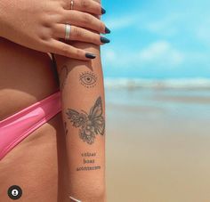 a woman's arm with tattoos on the beach