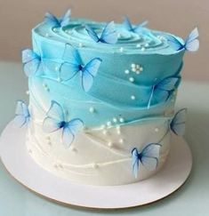 a blue and white cake with butterflies on it