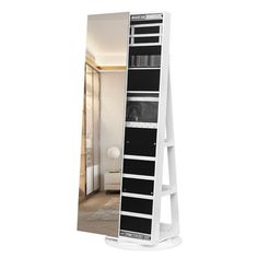 a tall white shelf with black drawers on it's sides and a mirror behind it