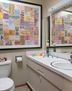 a bathroom with two sinks, a toilet and a large framed poster on the wall