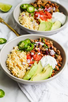 two bowls filled with rice, beans, avocado and sour cream on top