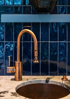 a copper sink and faucet in a blue tiled bathroom